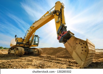 Big excavator on new construction site, in the background the blue sky and sun