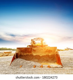 Big Excavator On New Construction Site, In The Background The Blue Sky And Sun