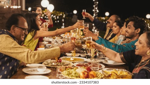 Big Family Celebrating Diwali: Indian Family in Traditional Clothes Gathered Together on a Dinner Table in a Backyard Garden Full of Lights, Making a Toast for Happiness on a Hindu Holiday - Powered by Shutterstock