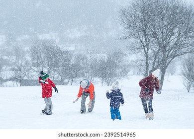 Big family with children play snowballs outside during snowfall. Winter fun holidays. Games in winter outdoors - Powered by Shutterstock