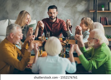 Big family father mother mature grandparents kids small girl boy gather sit table enjoy november feast meal pray celebrate thanksgiving day hold hands in house