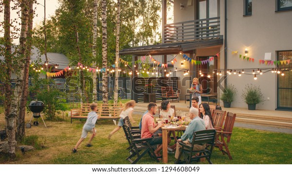 Big Family\
Garden Party Celebration, Gathered Together at the Table Family,\
Friends and Children. People are Drinking, Passing Dishes, Joking\
and Having Fun. Kids Run Around\
Table.