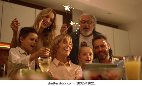 Big family singing christmas song at tablet camera during online video call. Smiling parents and children holding sparklers in hands. Joyful family congratulating relatives with happy new year online - Powered by Shutterstock