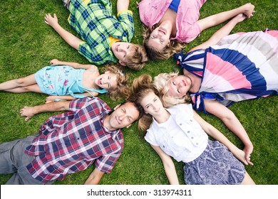 Big Family - Smiling Father, Mother, Grandma ,son And Two Daughters On The Green Grass In The Park.  Summer Holiday.