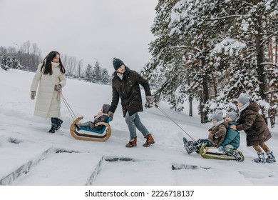 Big family spending fun time outdoors. Father pulling children on a sledge, on a cold snowy winter day. - Shutterstock ID 2226718137