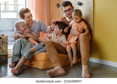Big family in sunny play room. Parents playing with kids and toys. Happy time together with games. Mother father son daughters at modern colorful home Three cute little children