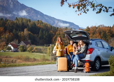 big family trip - happy girls travel by car. mamma with daughters sitting in the boot
