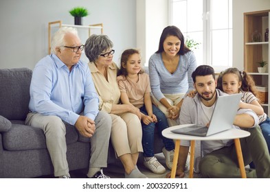 Big family using laptop computer and watching interesting movie all together. Young mom, dad, little kids and mature grandparents sitting on sofa at home and looking at screen of modern notebook PC - Powered by Shutterstock