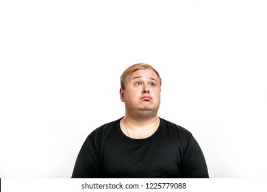 Big Fat Stout Blonde Man Dressed In Black T- Shirt Looking Up With Surprised Expression, Human Emotions Concept. Isolated On White Background With Copyspace.