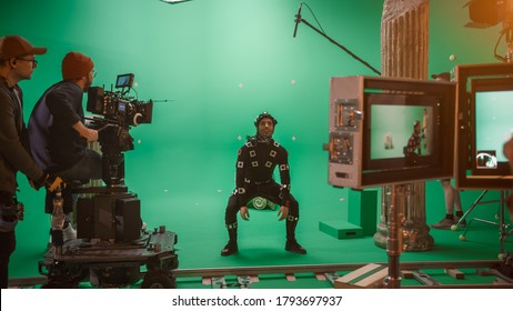 In the Big Film Studio Professional Crew Shooting Blockbuster Movie. Director Commands Camera Operator to Start shooting Green Screen CGI Scene with Actor Wearing Motion Tracking Suit and Head Rig - Shutterstock ID 1793697937