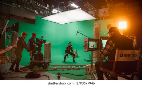In the Big Film Studio Professional Crew Shooting Blockbuster Movie. Director Commands Camera Operator to Start shooting Green Screen CGI Scene with Actor Wearing Motion Tracking Suit and Head Rig - Shutterstock ID 1793697946