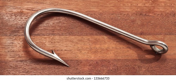 The Big Fishing Hook On Wooden Background.