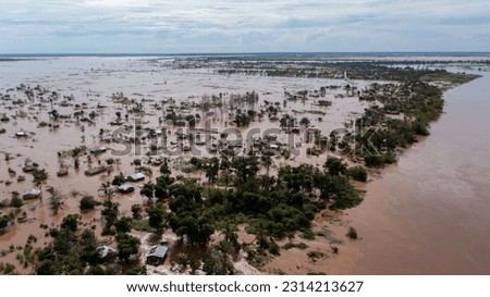 A big flood with trees and a village in the dirty waters in Africa