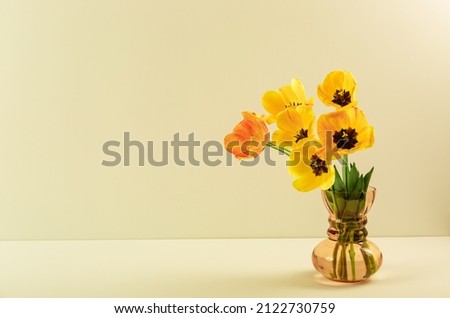 Big flowers bouquet of yellow tulips in vintage glass vase on beige color background. Copy space. Business card. Invitation postcard. Greeting text place. International holiday. Banner. Hello spring.