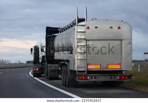 Big fuel tanker\
truck on roadside on heavy clouds baqckground. Dangerous goods\
cargo logistics in Europe