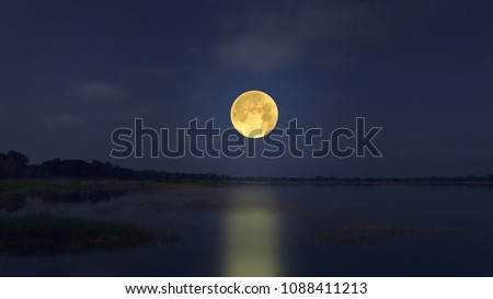 Big full moon in blue sky over the lake in the evening
