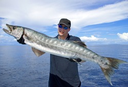 Big Game Fishing. Lucky  Fisherman Holding A Giant Barracuda