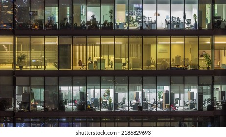 Big Glowing Windows In Modern Office Buildings Timelapse At Night, In Rows Of Windows Light Shines. People Working At Tables Inside