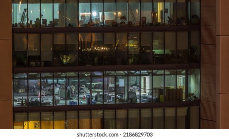 Big Glowing Windows In Modern Office Buildings Timelapse At Night, In Rows Of Windows Light Shines. Workers Make A Renovation Inside