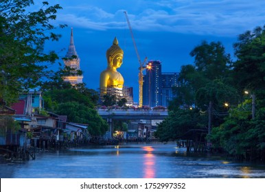 Big golden buddha statue under construction at Wat Paknam Bhasicharoen temple at  Twilight time, viewed from Klong Dan, Bangkok, thailand