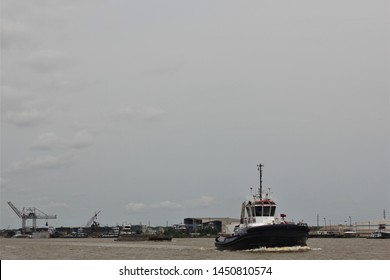 Big Grey Sky Above A Tug Boat Working On A Muddy Water Harbor