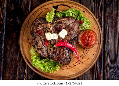 A Big Grilled Steak On A Wooden Plate, Top View