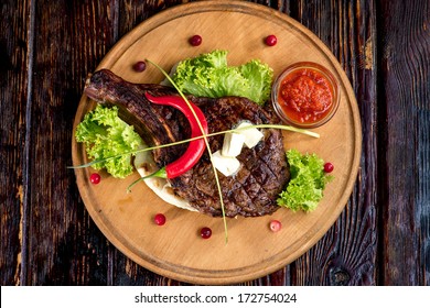 A Big Grilled Steak On A Wooden Plate, Top View