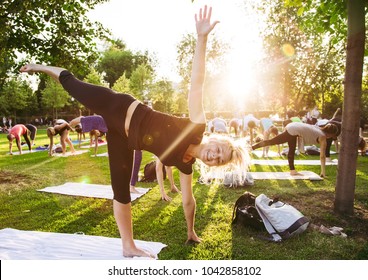 Big Group Of Adults Attending A Yoga Class Outside In Park