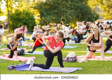 Big Group Of Adults Attending A Yoga Class Outside In Park