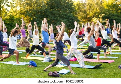 Big Group Of Adults Attending A Yoga Class Outside In Park