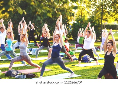 Big Group Of Adults Attending A Yoga Class Outside In Park