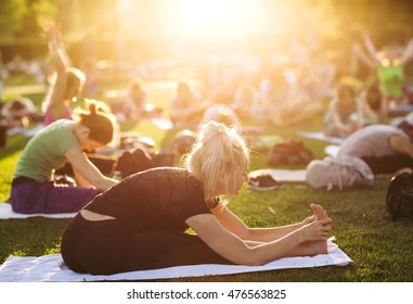 Big Group Of Adults Attending A Yoga Class Outside In Park