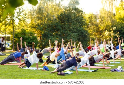 Big Group Of Adults Attending A Yoga Class Outside In Park