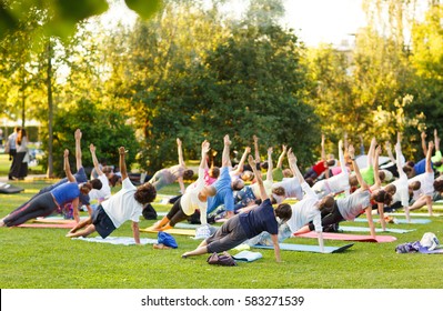 Big Group Of Adults Attending A Yoga Class Outside In Park