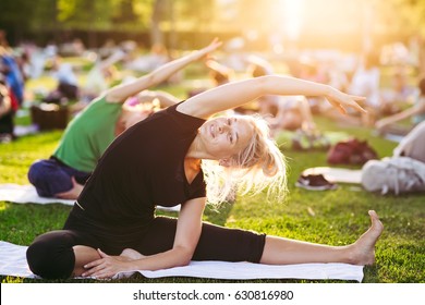 Big Group Of Adults Attending A Yoga Class Outside In Park