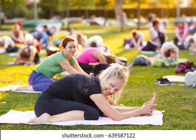 Big Group Of Adults Attending A Yoga Class Outside In Park