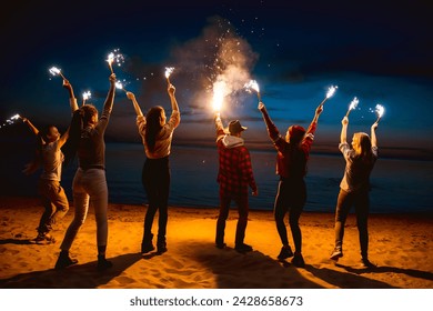 Big group of happy young friends are celebrating something and having fun with candles and sparklers at sunset lake beach - Powered by Shutterstock