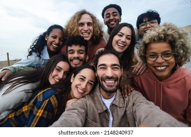 Big group portrait of diverse young people together outdoors - Multiracial happy millennial male and female friends having fun together - Unity and friendship concept - Focus on man in the center - Shutterstock ID 2148240937