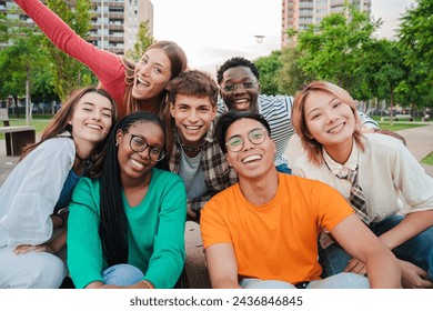 Big group of young adult real people smiling and having fun outdoors at vacations. Portrait of happy friends laughing. University teenage students on a social gathering. Multiracial teenagers meeting - Powered by Shutterstock