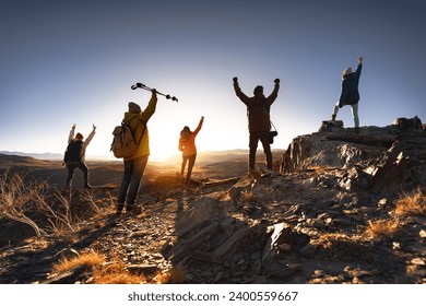 Big group of young hikers with backpacks are standing with open arms in winner poses at sunset mountain - Powered by Shutterstock