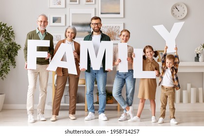 Big happy family in new house. Grandparents, mother and father with little kids holding word FAMILY and smiling at camera while standing in new modern appartment. Mortgage and real estate concept - Powered by Shutterstock