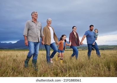 Big happy family walking on field, meadow and countryside in nature to relax, bond and holding hands in love, trust and support. Generation of grandparents, parents and kids having fun outside - Powered by Shutterstock