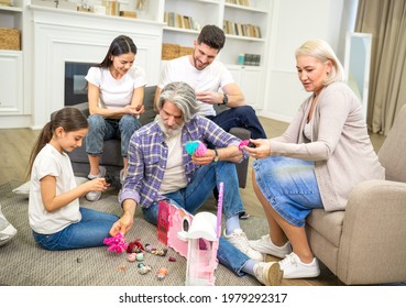 Big Happy Multigenerational Family Father Mother And Grandparents Playing With Cute Little Girl Granddaughter, Looking At New Dollhouse, Having Fun And Relaxing Together On Weekend At Home