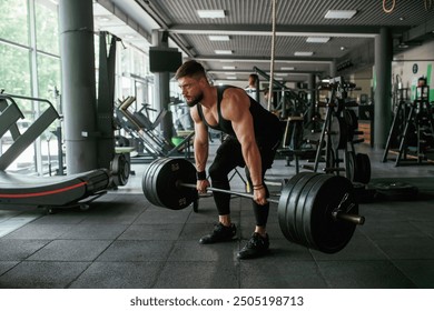 Big and heavy barbell in hands. Strong muscular man is working out in the gym. - Powered by Shutterstock