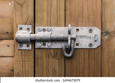 Big heavy metal door bolt latch affixed to a wooden door shot straight on.