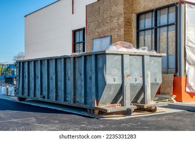 A big, heavy-duty dumpster next to a new fast food restaurant under construction.
