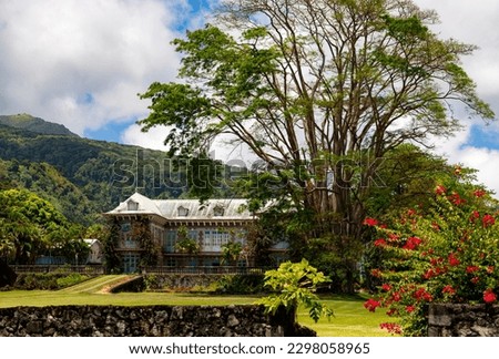 Big historic manor house in Saint Pierre on Martinique island (France) with opulent old garden and tropical vegetation. Mount Pelée volcano in background. Public museum and caribbean rum distillery.