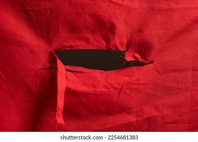 big hole cut open in a red fabric texture, shredded hole at center of a red flag - Powered by Shutterstock