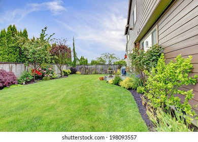 Big House With Walkout Small Deck. View Of Lawn And Flower Bed