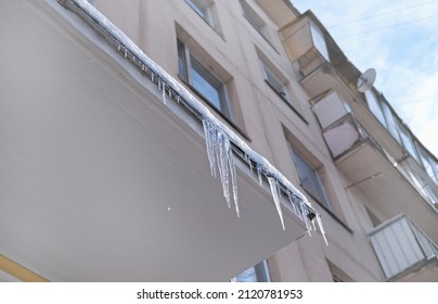 Big Icicles Above The Entrance To A Residential Building In Moscow. Hanging Icicles Above The Entrance To A Building, Risk To Life. Sharp Icicles Hang From The Roof Of An Old Apartment Building